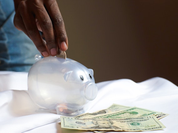 hand placing money into a clean piggy bank